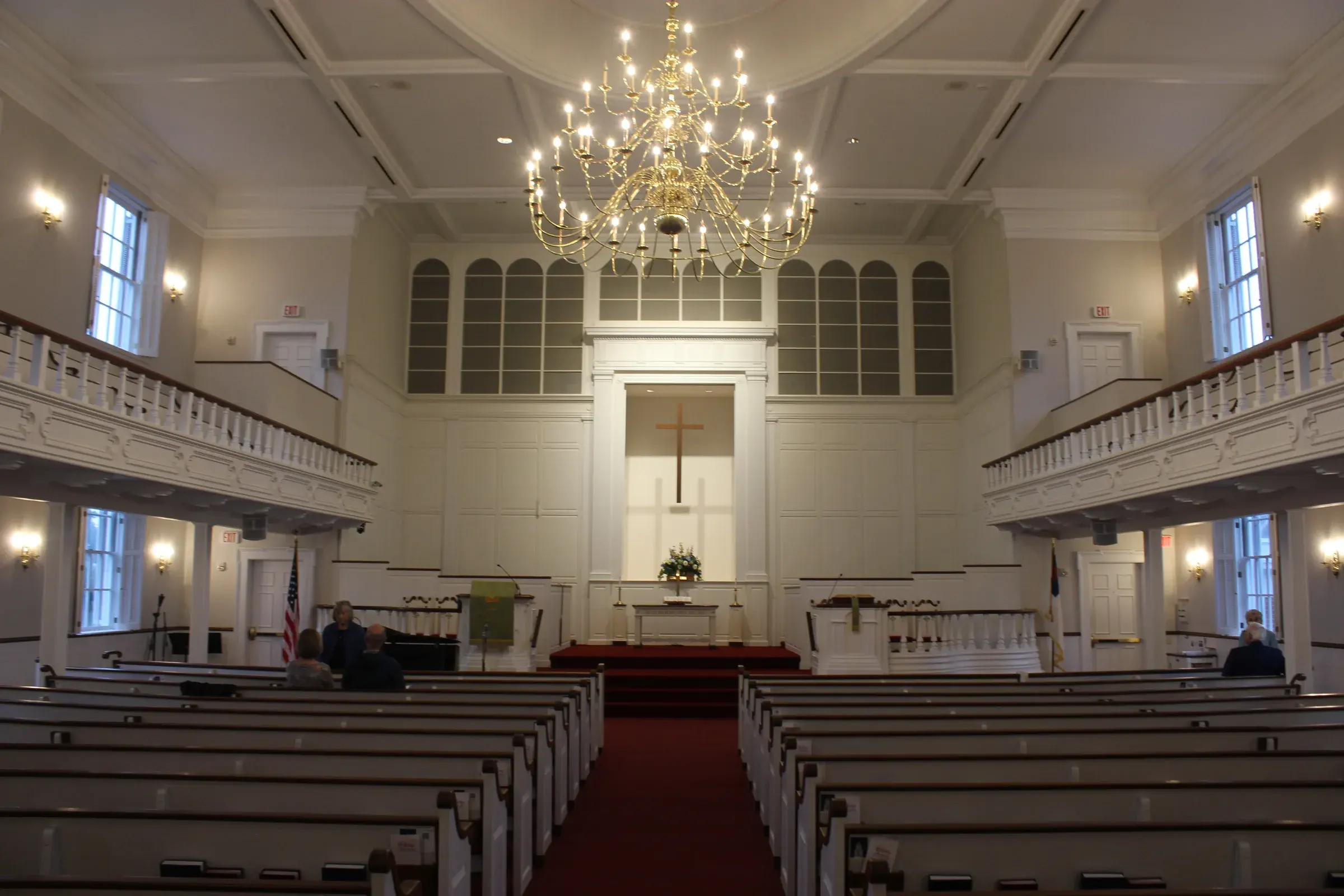 The sanctuary of Second Baptist Church of Suffield, looking down the center aisle toward the cross beneath the brass chandelier